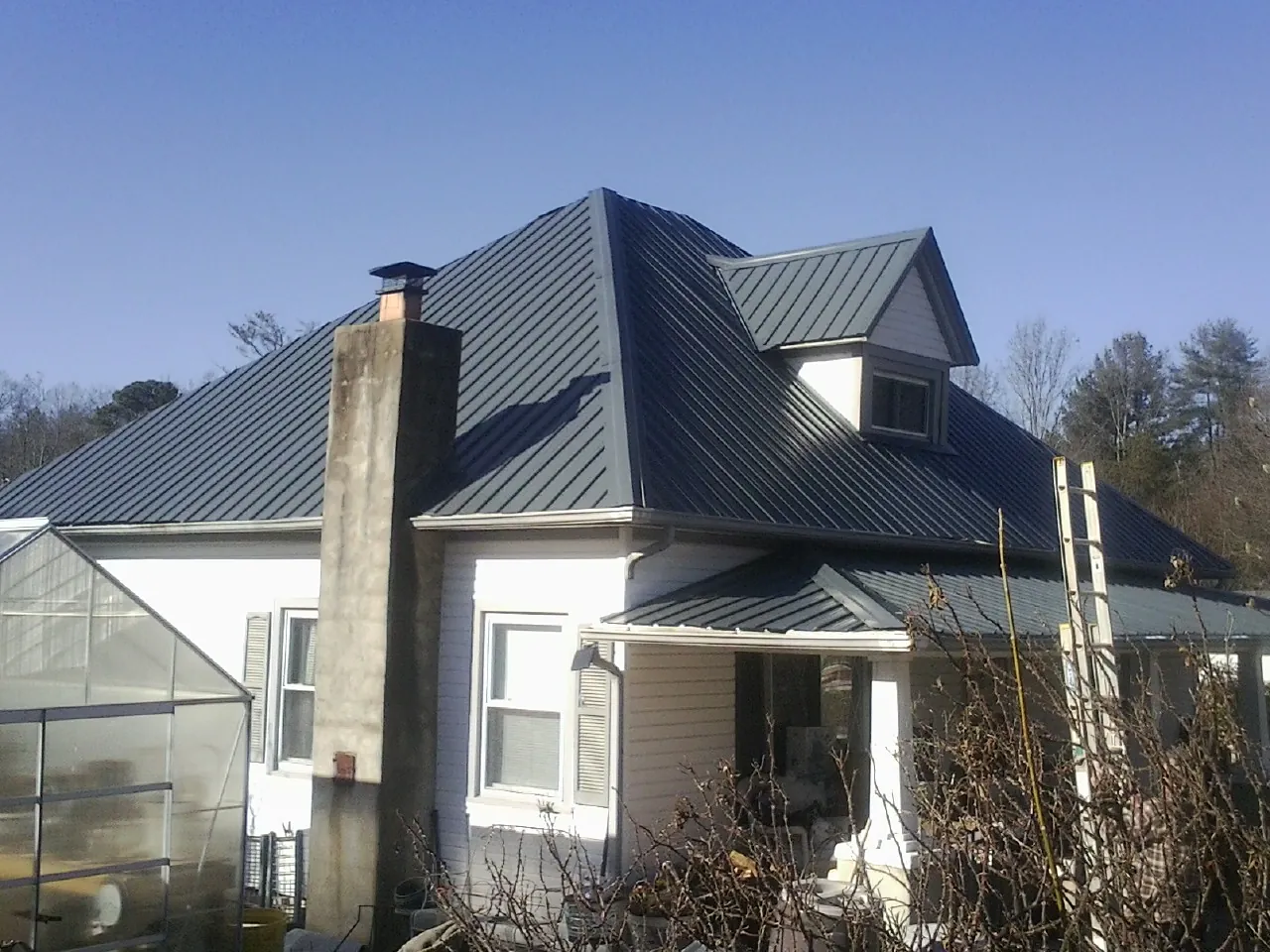 Dark blue standing seam metal roof on a white farmhouse with dormer — Slate & Tile Roof Repair by Roofing Brothers in Welda