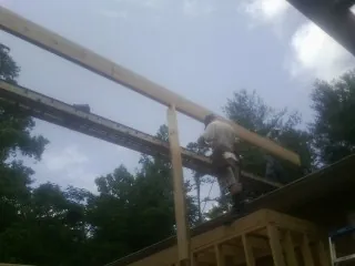 Carpenter setting a ridge beam over a new addition frame — Ice Dam Removal by Roofing Brothers in Welda
