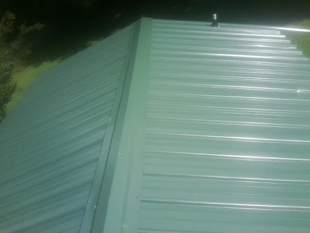 New green metal panels meeting at the ridge of a roof — Flat Roof Repair work by our crew in Welda