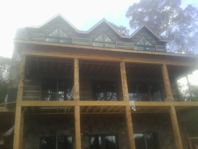 Dormers and porch framing on a large log home under construction — Roof Coating work by our crew in Welda