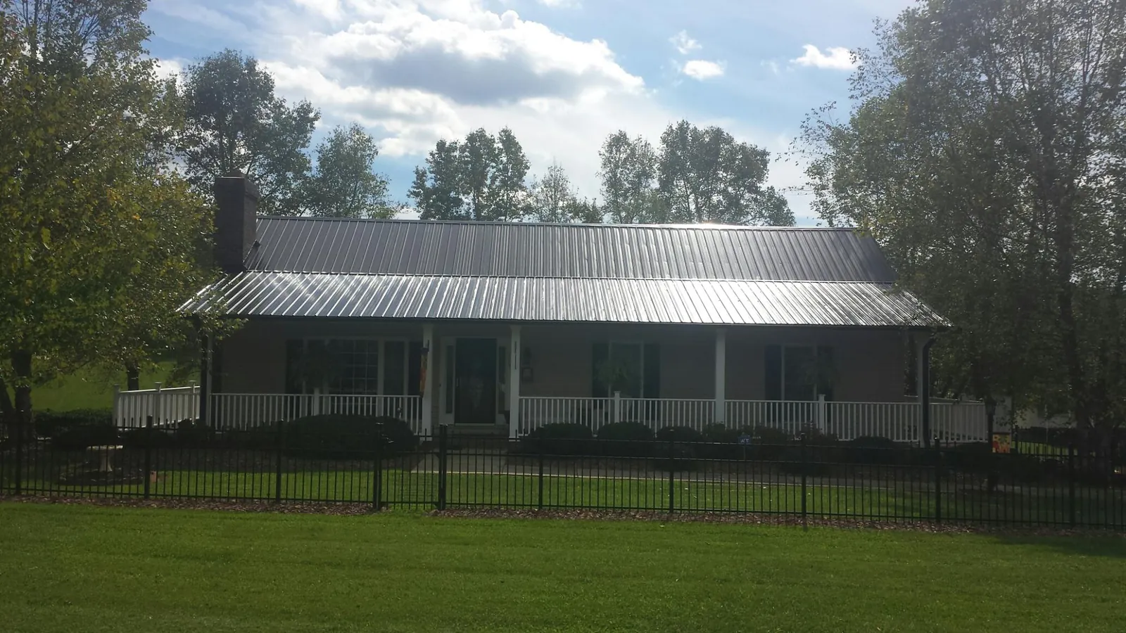 Gray metal roof on a brick ranch with a full width front porch — Gutter Guard Installation work by our crew in Welda