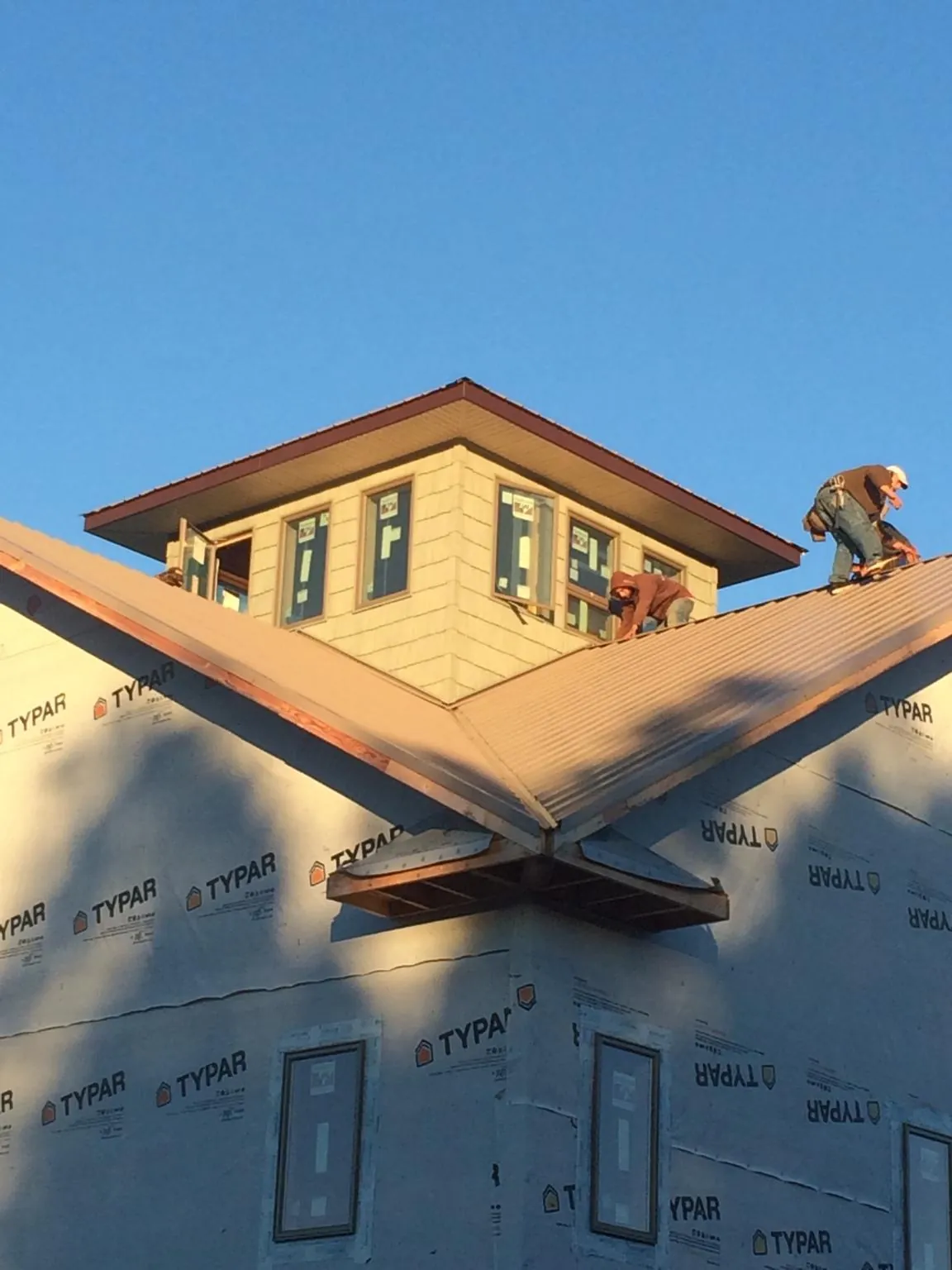 Roofers working around a rooftop cupola on a new metal roof at sunset — Roof Waterproofing in Welda by Roofing Brothers